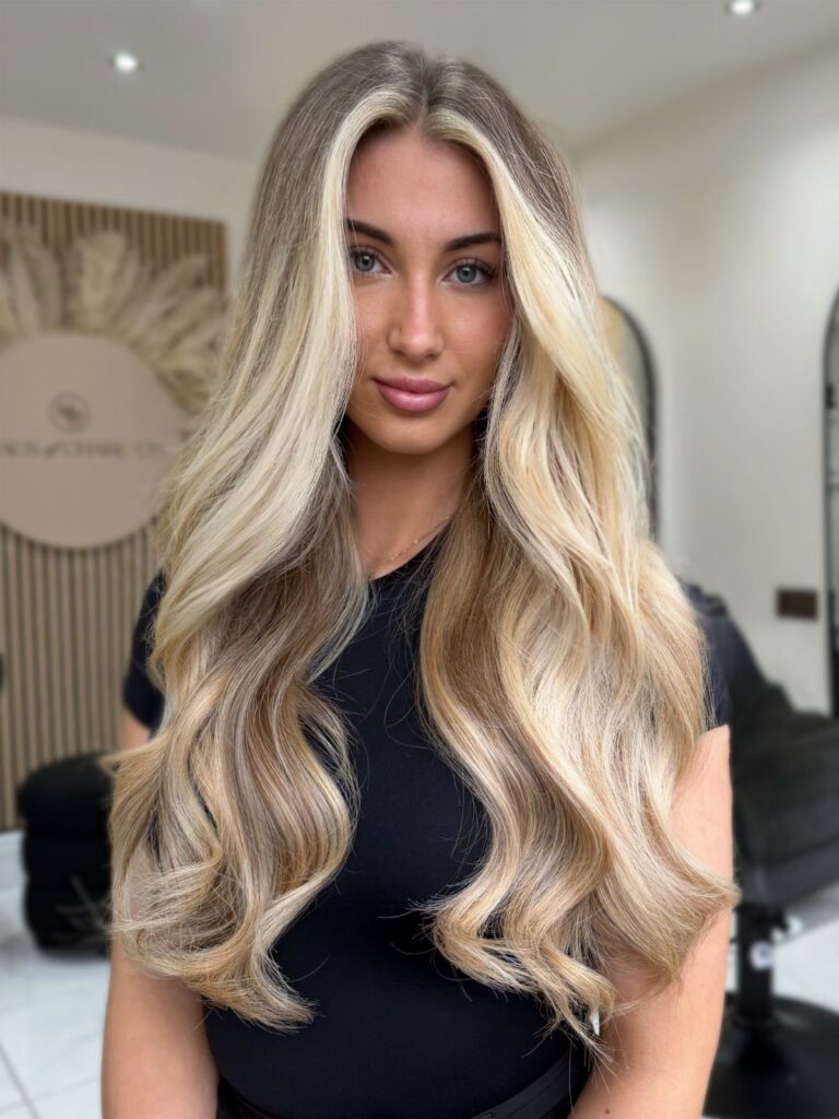 Woman with long wavy blonde hair and bright blonde highlights framing her face.