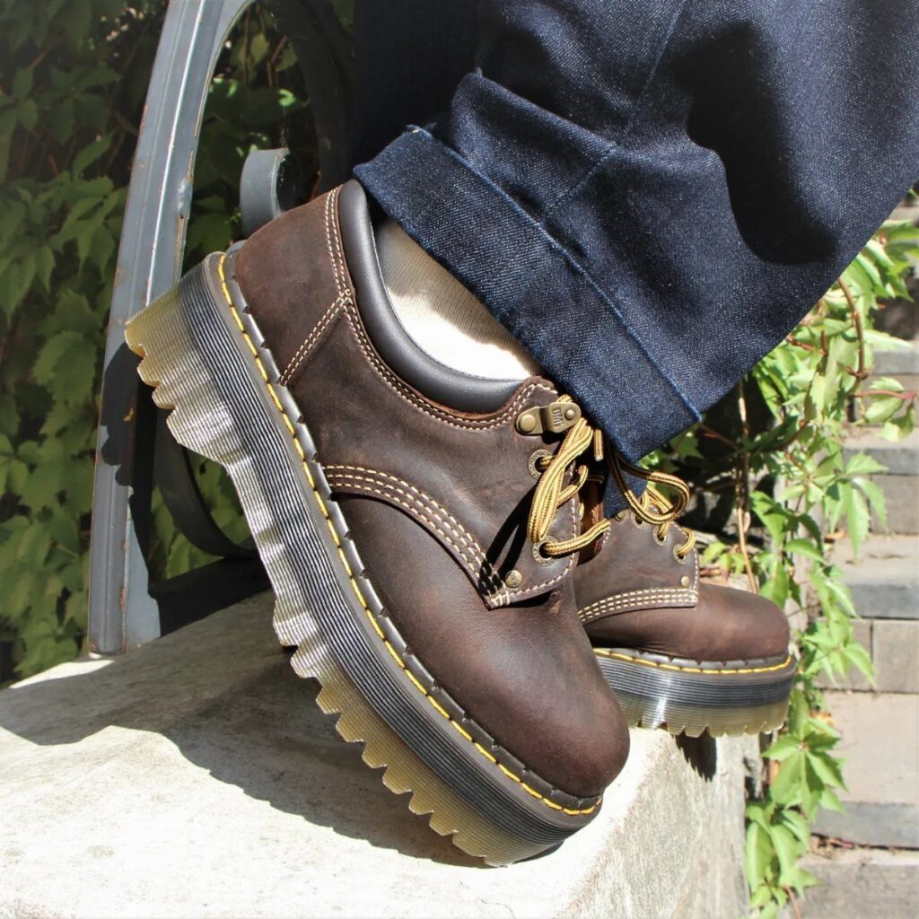 Brown leather platform casual shoes with thick soles and yellow stitching on feet.