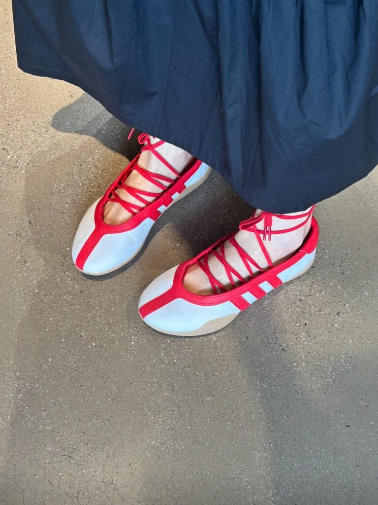 White and red Adidas ballerina shoes with red laces on a concrete floor