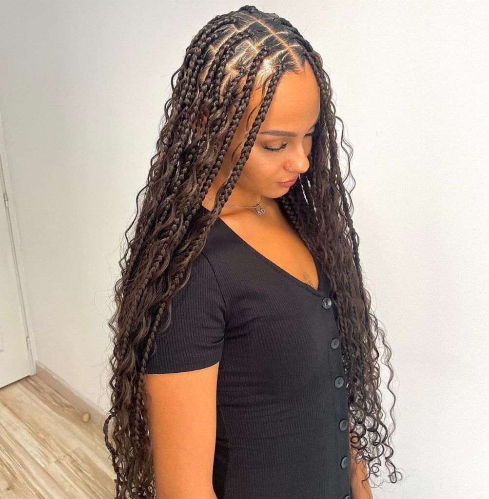 Woman with long dark brown goddess braids with curly ends and loose curls.