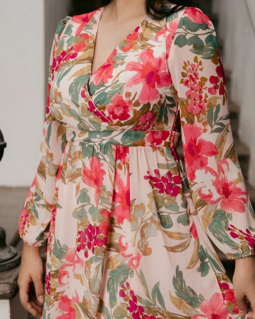 Woman wearing a light pink gown with a vibrant red and green floral print.
