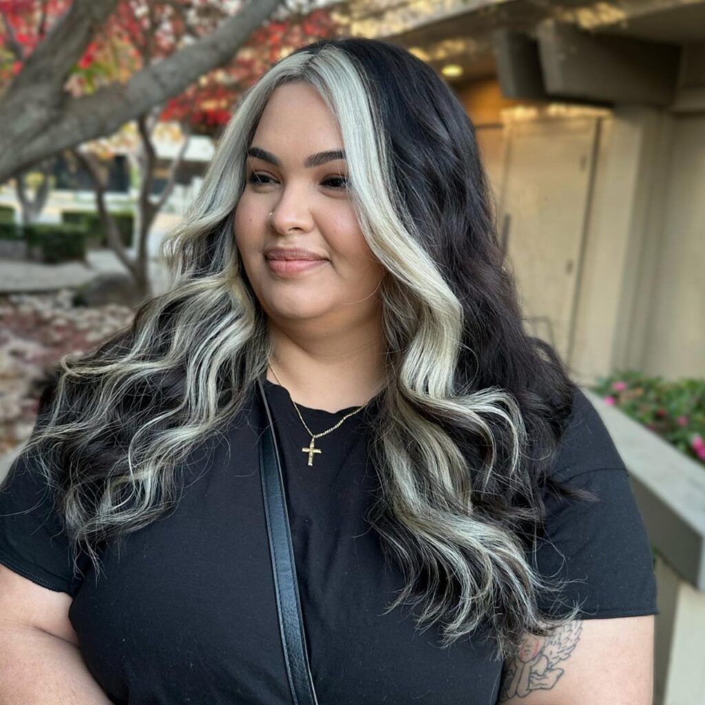 Woman with long wavy hair dyed in black and platinum blonde block coloring.