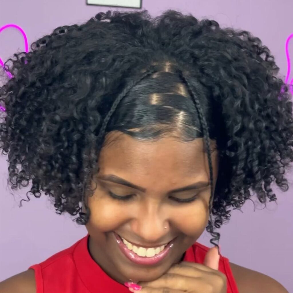 Woman with voluminous curly afro hair and small braids smiling against purple background