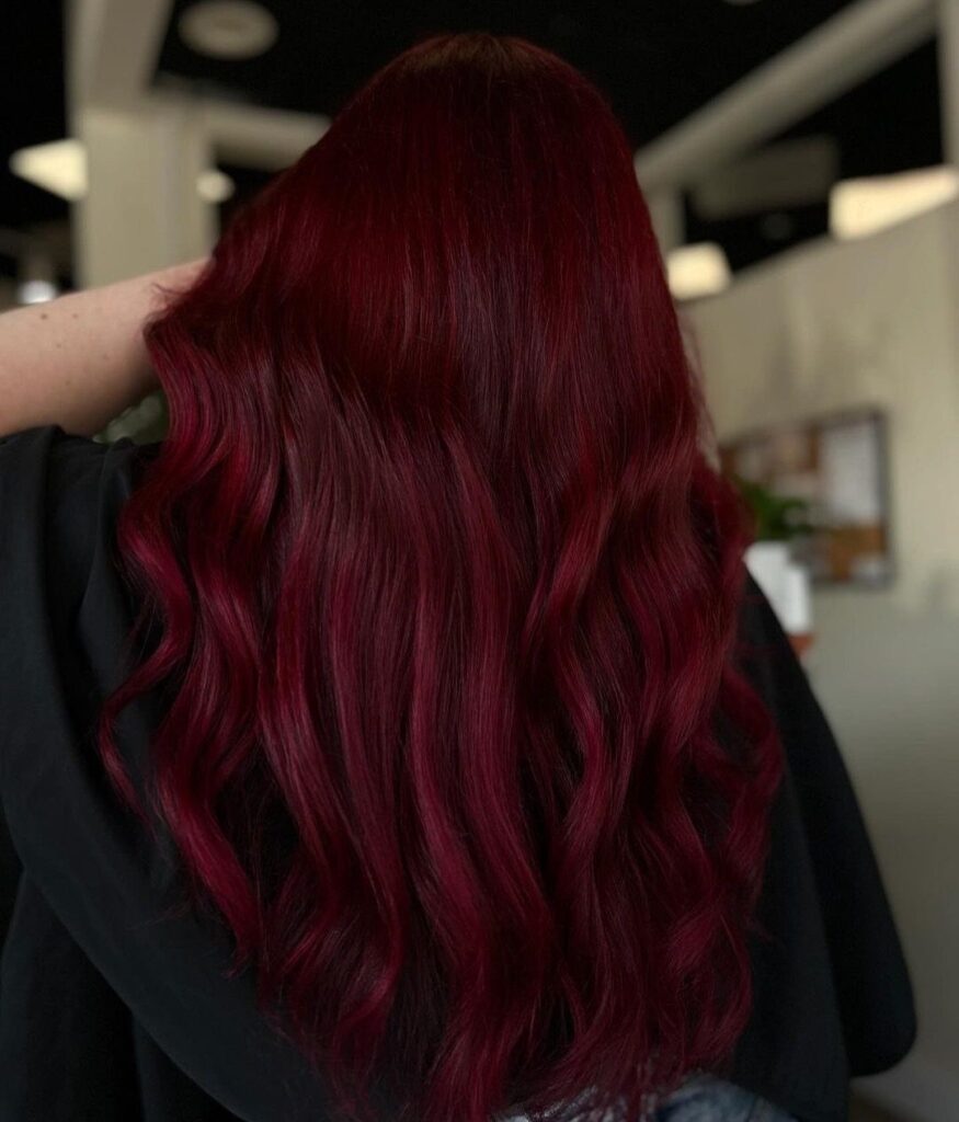 Long wavy deep red burgundy hair seen from the back of a person.