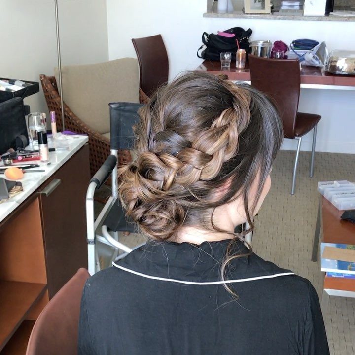 Brown hair styled in an intricate braided crown up-do in a salon setting