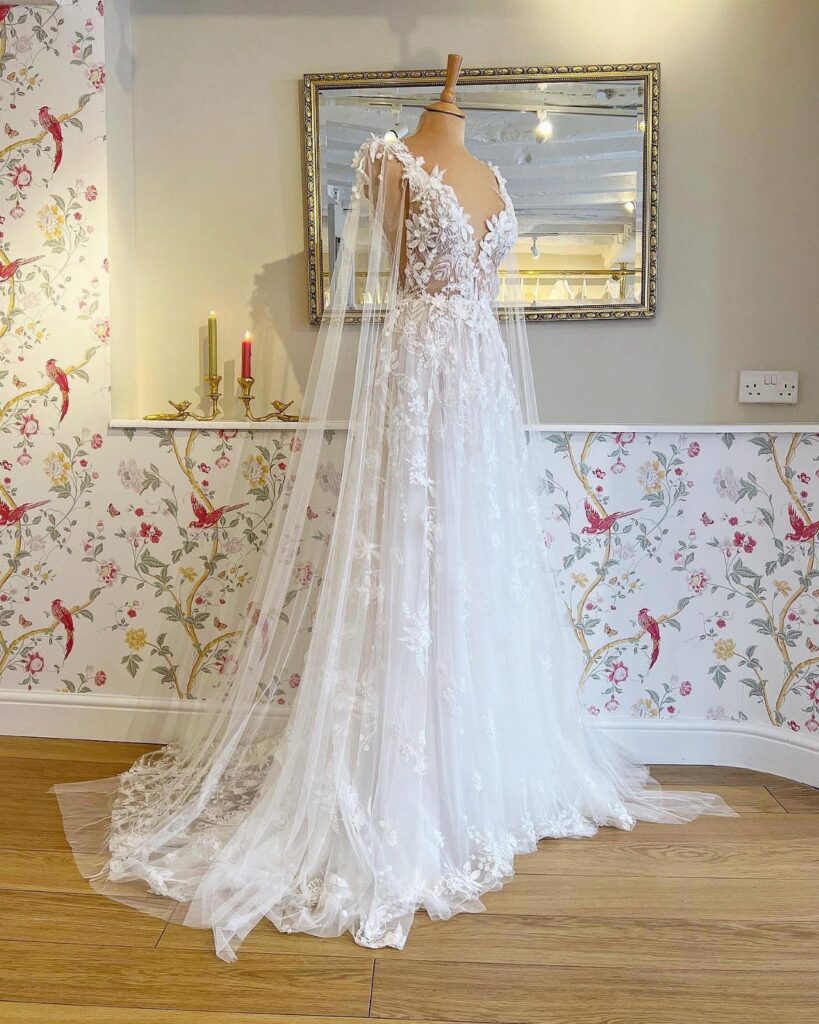 White floral lace wedding gown with a long veil on a mannequin.