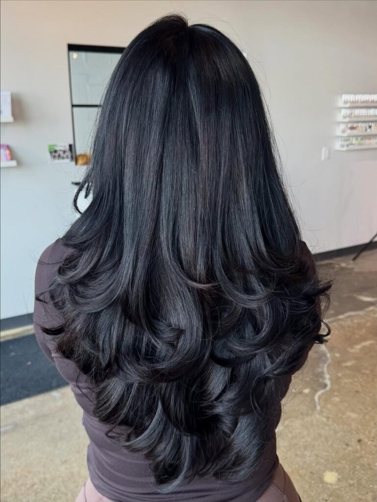 Long thick black hair styled with voluminous curled layers seen from behind