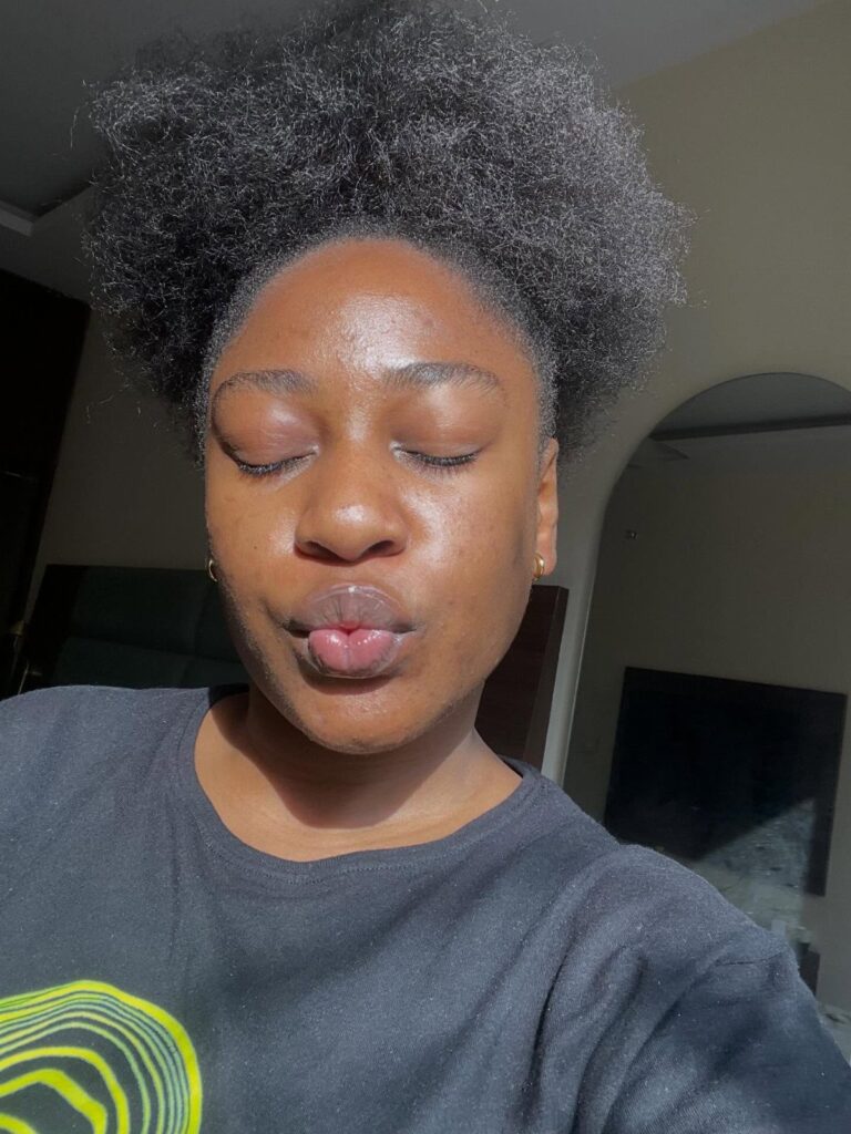 Black woman with a voluminous natural afro posing with eyes closed and pursed lips.