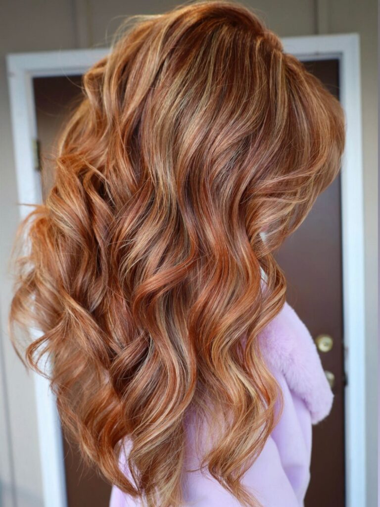Long wavy hair with a blend of golden blonde and copper red tones.