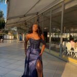 Woman in a navy blue sequined prom dress with a high leg slit.