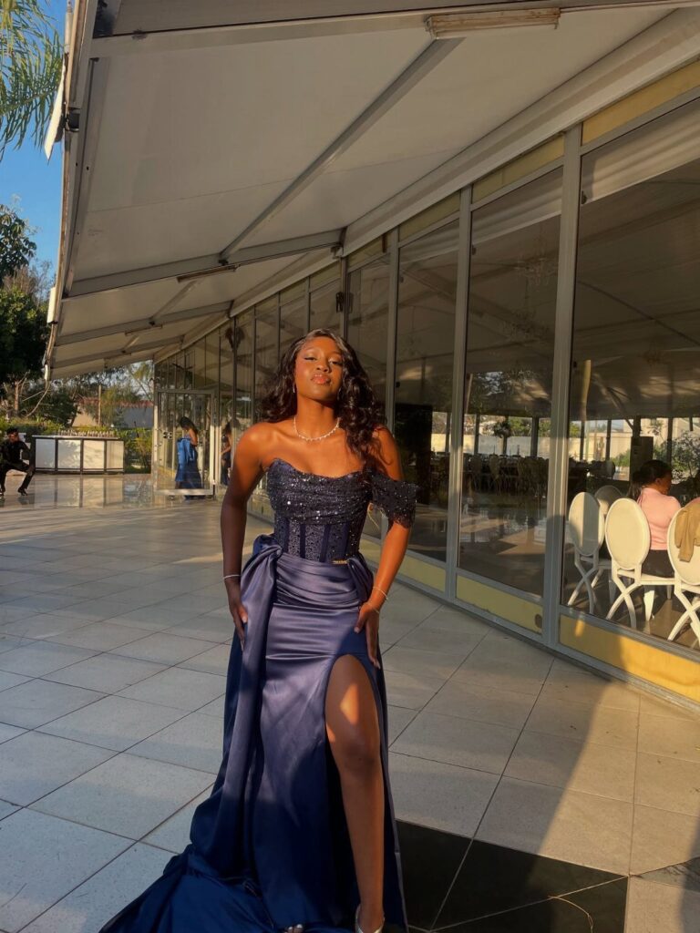 Woman in a navy blue sequined prom dress with a high leg slit.