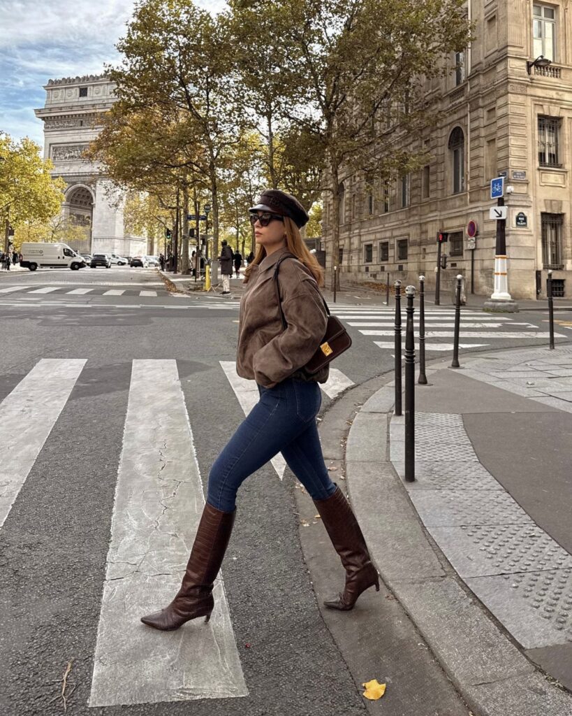 Woman wearing blue skinny jeans and brown slouchy boots walking in Paris.