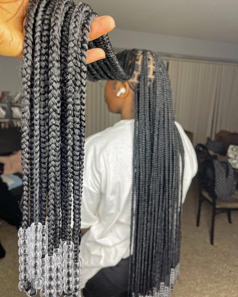 Long black box braids with clear plastic beads at the ends.